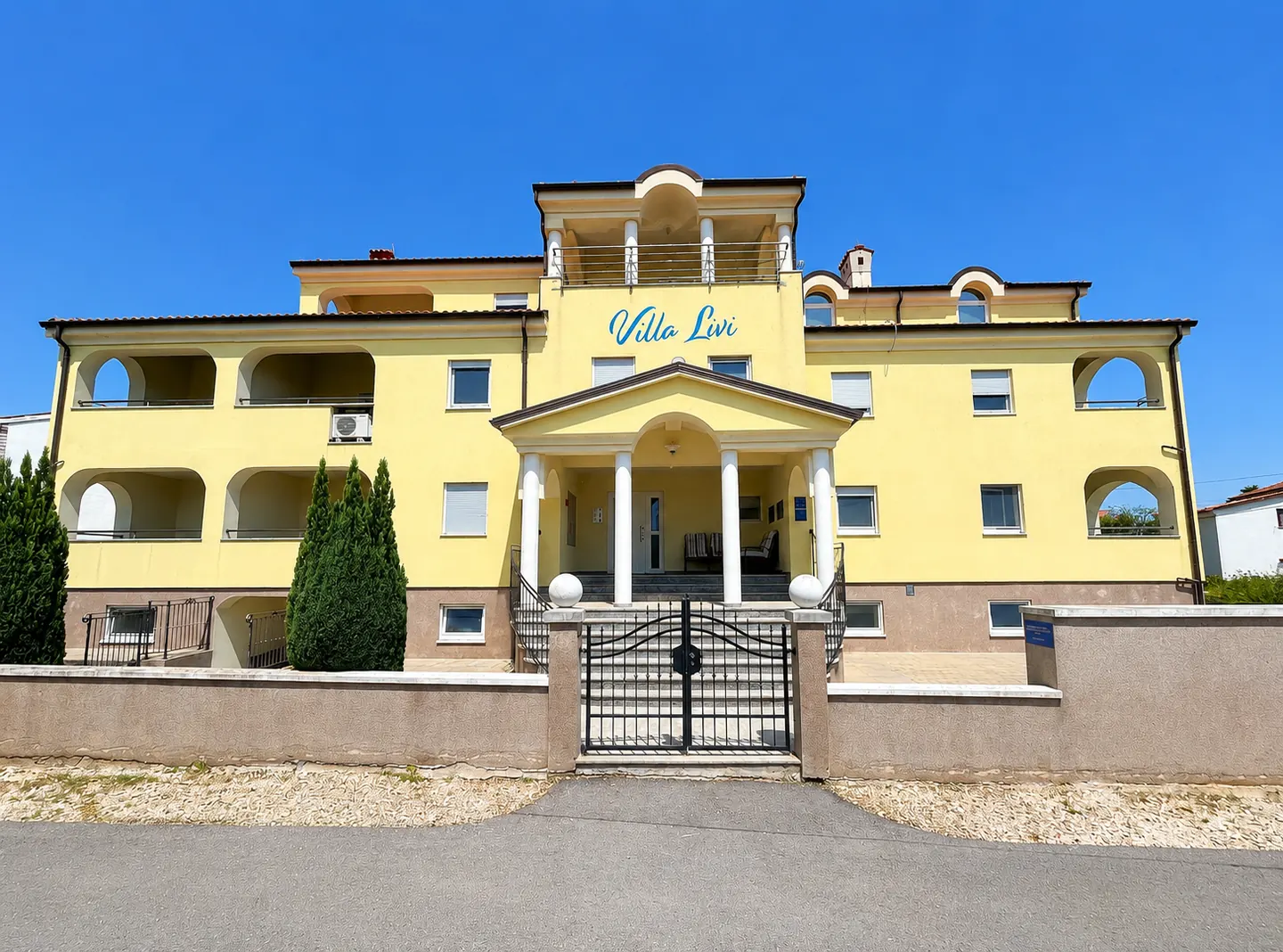 Pročelje Ville Livi, žute apartmanske kuće u Medulinu s plavim natpisom